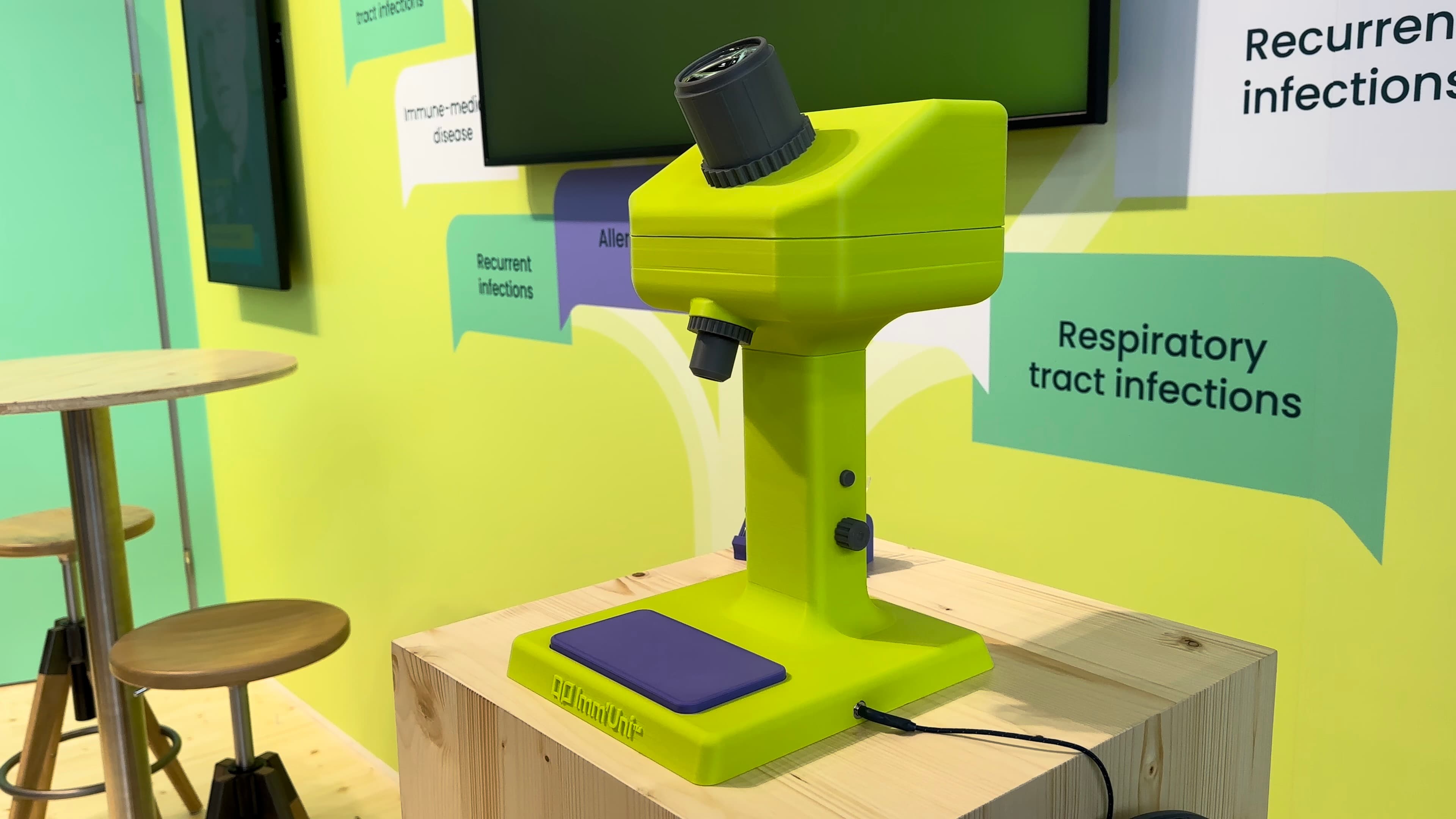 Microscopio stampato in 3D color lime con piatto viola per i vetrini, sullo stand OM Pharma al congresso